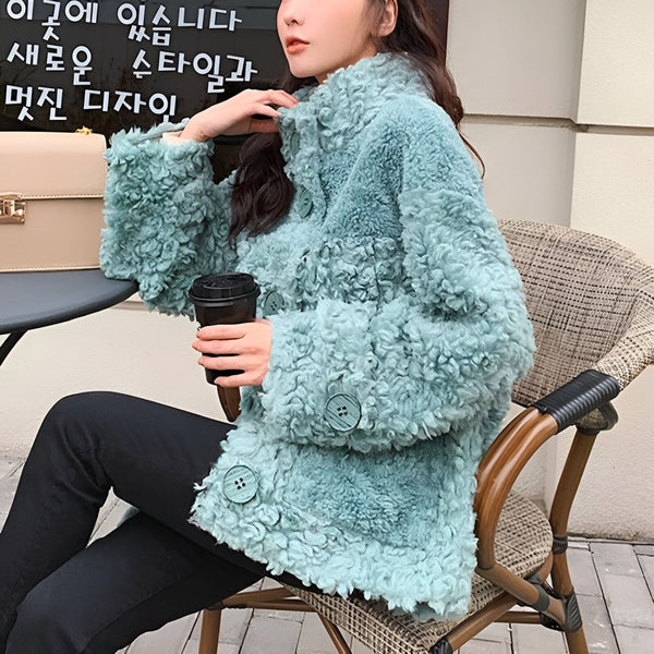 Femme assise portant un manteau en fausse fourrure turquoise avec de gros boutons. Kimono d'extérieur confortable et élégant.