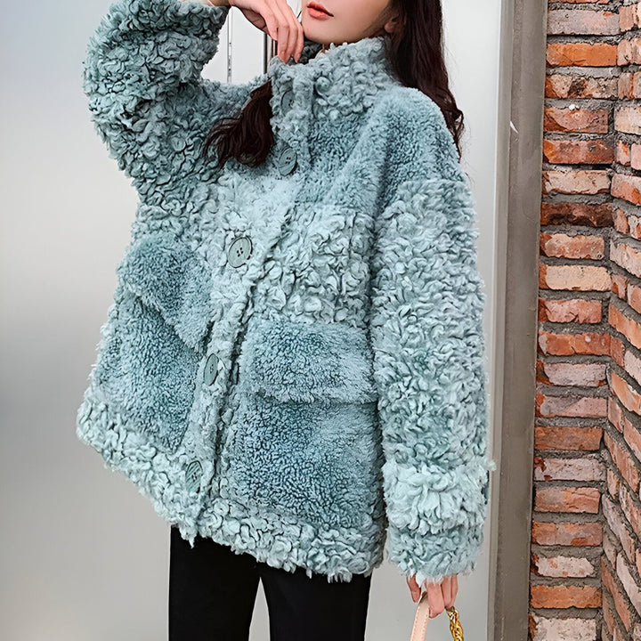 Femme portant un manteau kimono bleu turquoise à texture bouclée avec boutons et poches. Vêtements d'hiver chauds et élégants.