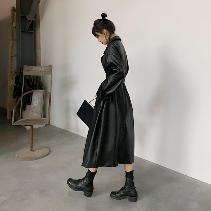 Femme portant un long kimono en cuir noir avec des bottes assorties. Style moderne inspiré du kimono traditionnel. Découvrez notre collection de kimonos uniques.