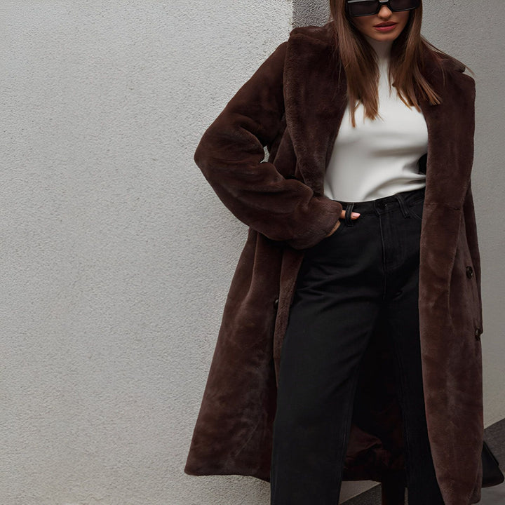 Femme élégante portant un long kimono marron en fausse fourrure, avec un col roulé blanc, un jean noir et des lunettes de soleil tendance. Découvrez notre collection de kimonos.