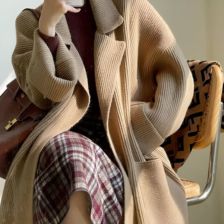 Femme portant un long kimono beige en tricot. Détails de son style : pull bordeaux, jupe à carreaux, sac en cuir marron. Collection de kimonos modernes pour femme.