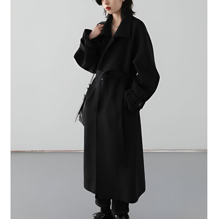 Femme portant un long manteau noir ceinturé, style kimono moderne. Vêtements d'extérieur d'inspiration japonaise. Boutique de kimonos en ligne.