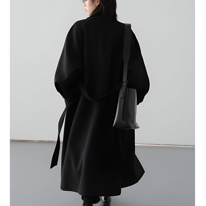 Femme portant un kimono noir long avec une ceinture assortie et un sac noir sur l'épaule. Mode kimono, style japonais.