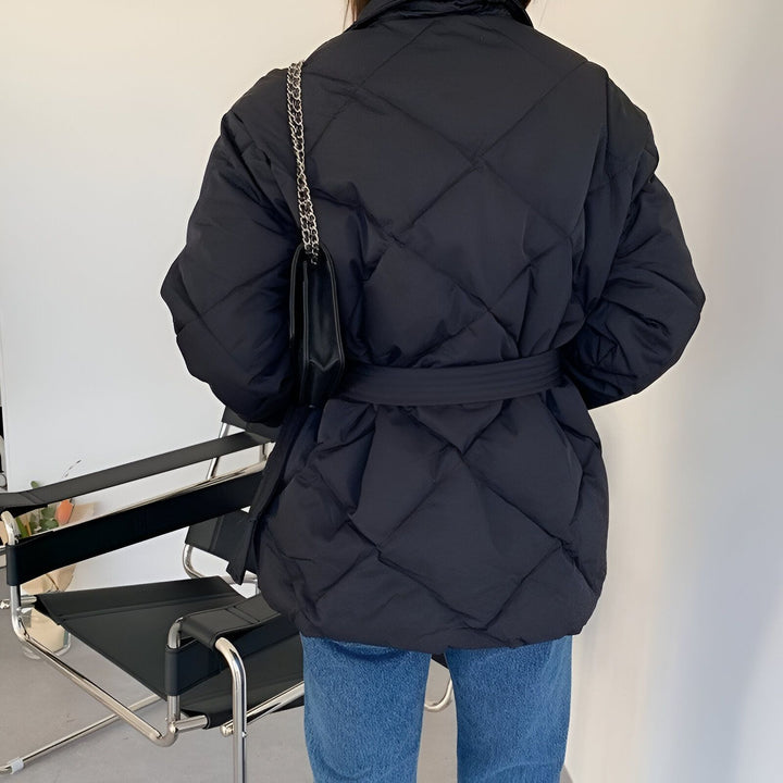 Veste kimono noire matelassée avec ceinture, vue de dos. Sac à main noir à chaîne. Mode femme.