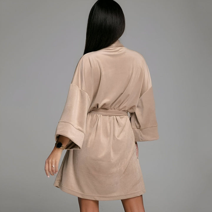 Femme de dos portant un kimono beige en velours, manches larges et ceinture à la taille. Vêtements de détente et d'intérieur, style japonais moderne.