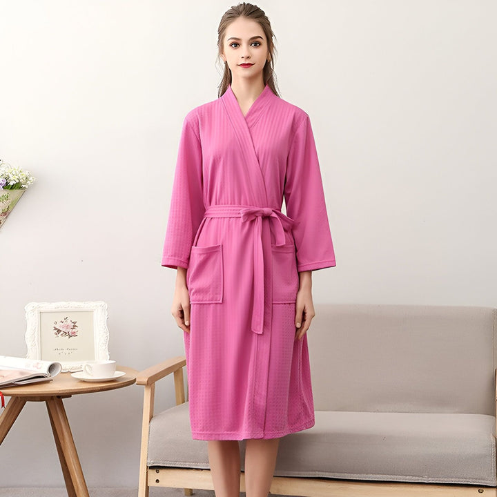 Femme portant un kimono rose avec ceinture. Peignoir kimono de notre collection, idéal pour la maison ou comme vêtement d'intérieur. Achetez votre kimono préféré en ligne.