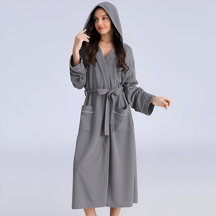 Femme portant un kimono gris à capuche avec ceinture. Peignoir long confortable, idéal après le bain ou pour se détendre à la maison. Kimonos disponibles dans différents styles et couleurs sur notre boutique en ligne.