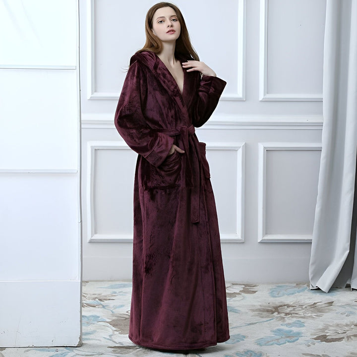 Femme portant un long kimono bordeaux en velours avec capuche. Peignoir élégant et confortable, idéal après le bain. Découvrez notre collection de kimonos pour femmes.