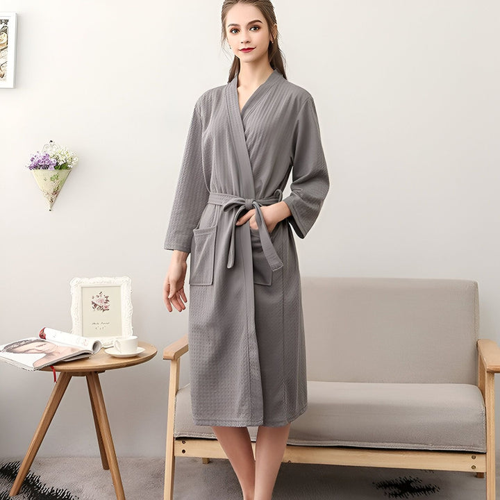Femme portant un kimono gris confortable avec ceinture. Peignoir élégant pour la maison. Collection de kimonos doux et relaxants.
