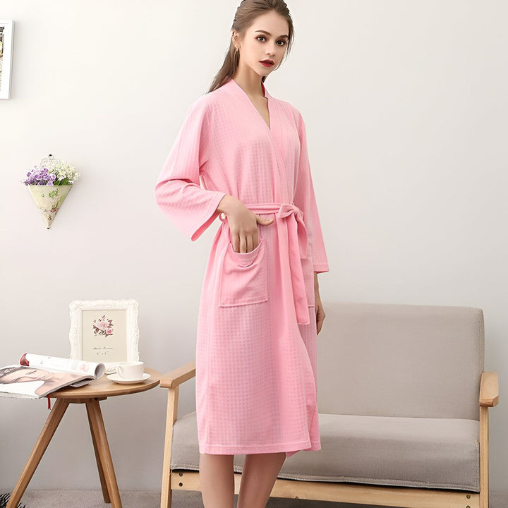 Femme portant un kimono rose confortable avec ceinture. Notre boutique propose une large sélection de kimonos élégants.