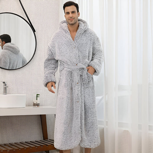 Homme portant un peignoir kimono gris et moelleux avec capuche dans une salle de bain lumineuse. Le peignoir est noué à la taille et a des poches. Idéal pour la détente et le confort après le bain.