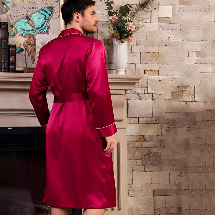 Homme portant un kimono en satin rouge bordeaux avec ceinture, devant une cheminée. Vente de kimonos en ligne.