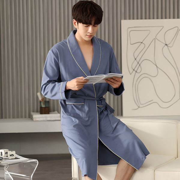 Homme asiatique en kimono bleu lisant. Vente de kimonos en ligne. Confort et style japonais. Découvrez notre collection de kimonos pour hommes.