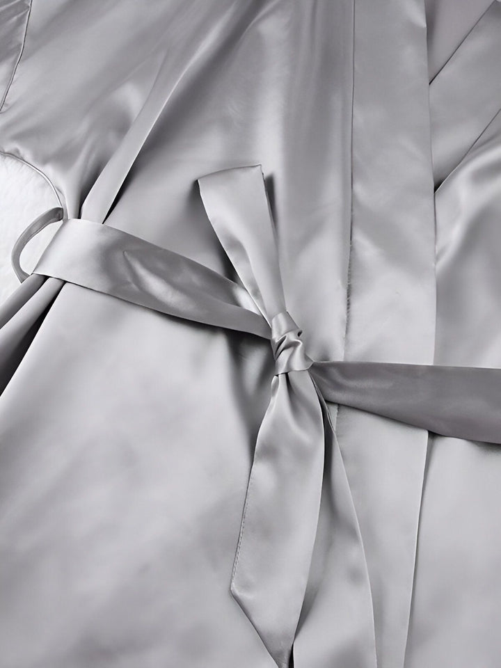 Détail d'un kimono gris argenté avec ceinture nouée. Texture soyeuse et élégante. Parfait pour se détendre avec style. Découvrez notre collection de kimonos.