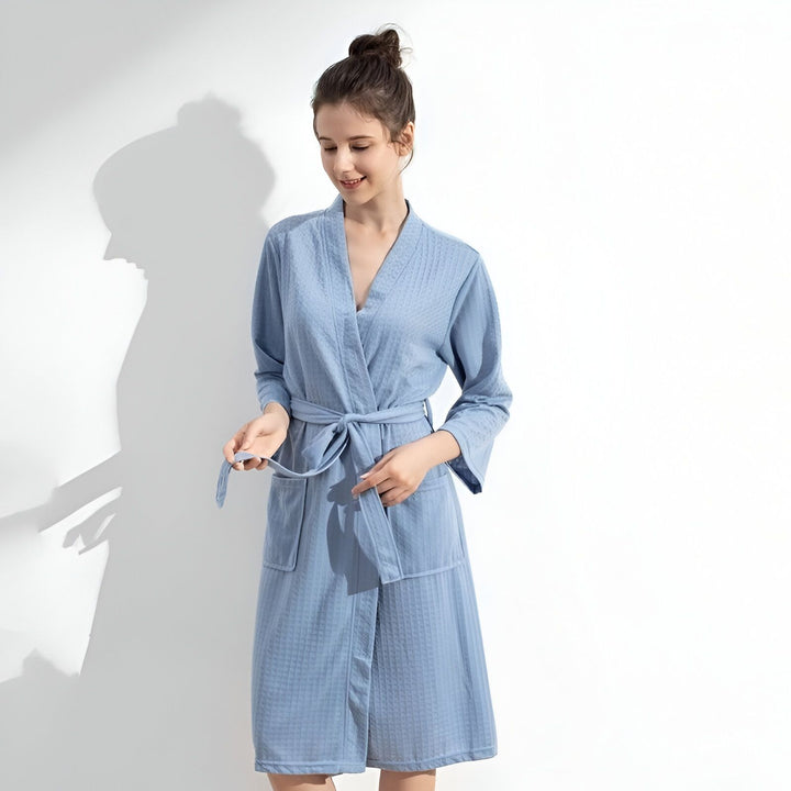 Femme portant un kimono bleu clair. Kimono confortable avec ceinture. Idéal pour se détendre après le bain ou la douche. Découvrez notre collection de kimonos.