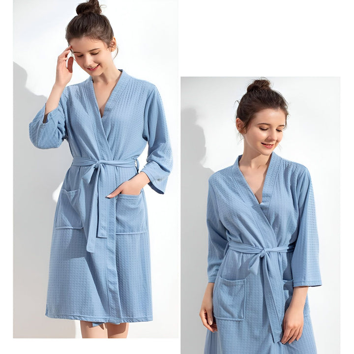 Femme portant un kimono bleu clair à motif gaufré. Peignoir doux avec ceinture et poches, parfait pour se détendre. Kimono pour la maison, disponible à l'achat.
