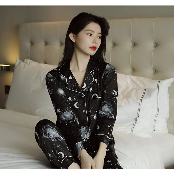 Femme asiatique portant un pyjama kimono noir à motifs d'étoiles et de lunes, assise sur un lit blanc. Vêtements de nuit confortables.