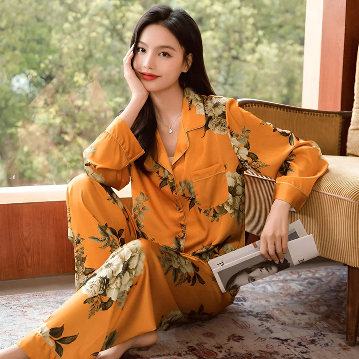 Femme asiatique portant un kimono pyjama fleuri orange, assise sur un tapis. Kimono pour femme, vêtements de nuit élégants. Découvrez notre collection de kimonos.