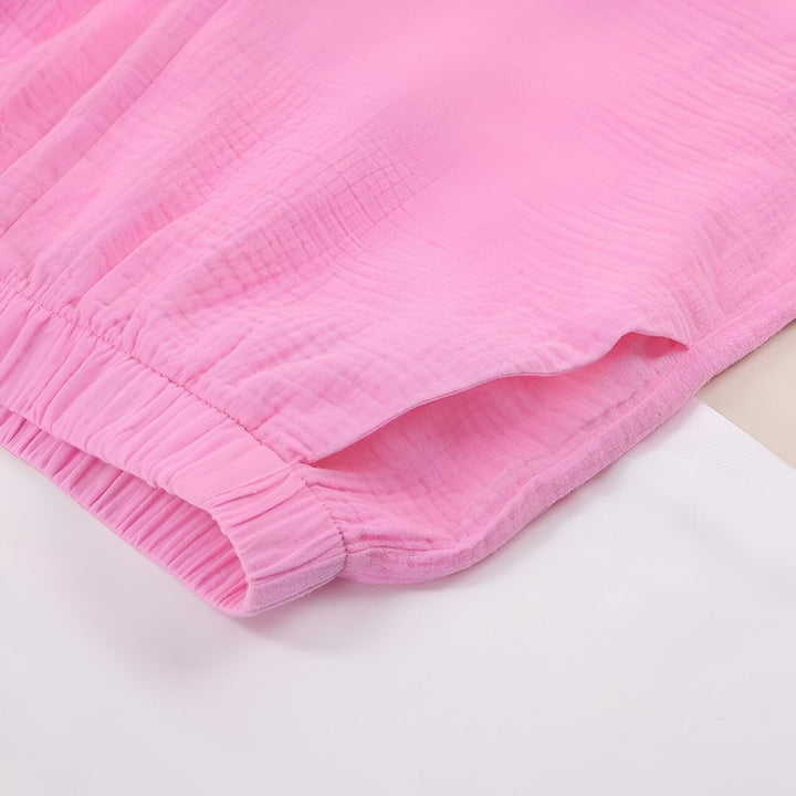 Détail d'un vêtement rose style kimono avec une poche et une taille élastique. Texture du tissu gaufrée. Vêtements kimono pour femme, confort et style.