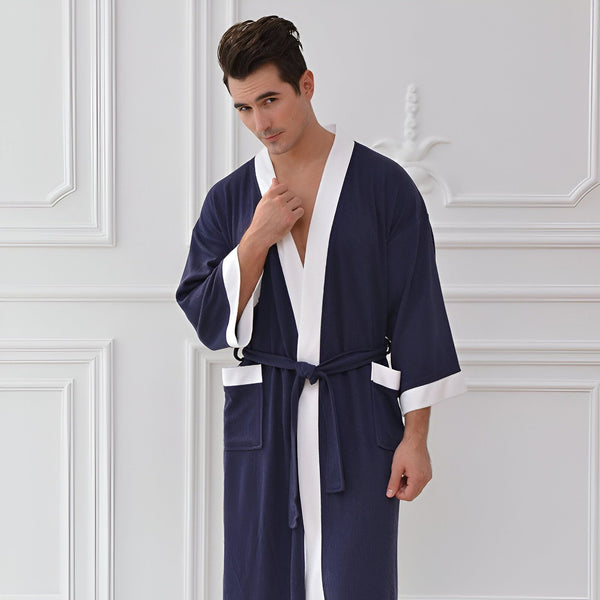 Homme portant un kimono bleu marine avec des bordures blanches. Peignoir confortable et élégant. Nos kimonos de qualité supérieure pour hommes.