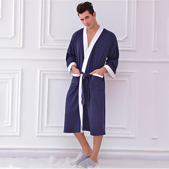 Homme portant un kimono bleu marine avec des bordures blanches. Peignoir kimono confortable pour la maison. Découvrez notre collection de kimonos pour hommes.