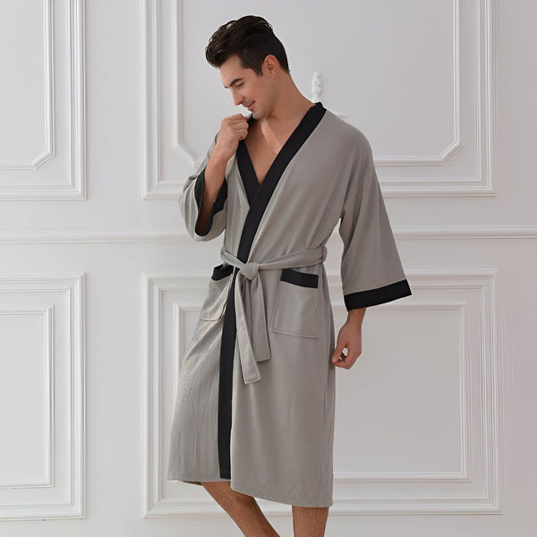 Homme portant un kimono gris avec bordure noire et ceinture. Vêtements de détente élégants.