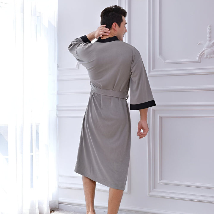 Homme portant un kimono gris avec bordure noire. Vente de kimonos pour hommes. Kimono confortable et élégant. Nos kimonos de qualité supérieure.