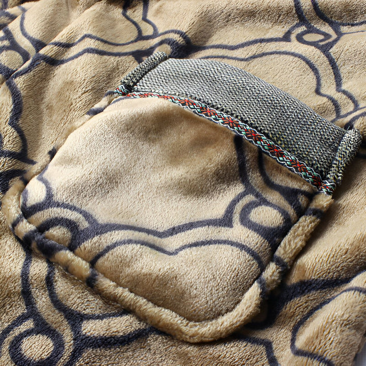 Détail d'un kimono en tissu éponge beige avec motif ondulé. Une poche plaquée avec rabat en tweed et bordure décorative ajoute une touche élégante. Parfait pour se détendre avec style.