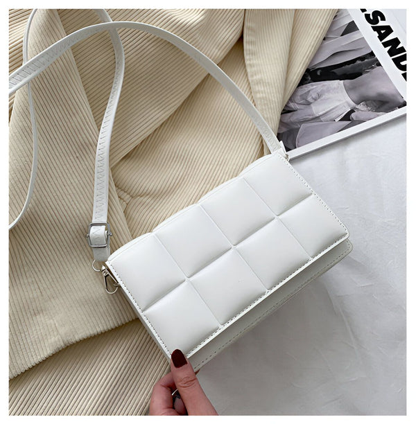 Sac à bandoulière blanc matelassé, accessoire de mode élégant avec une texture géométrique distinctive. Idéal pour compléter une tenue avec une touche de sophistication moderne.
