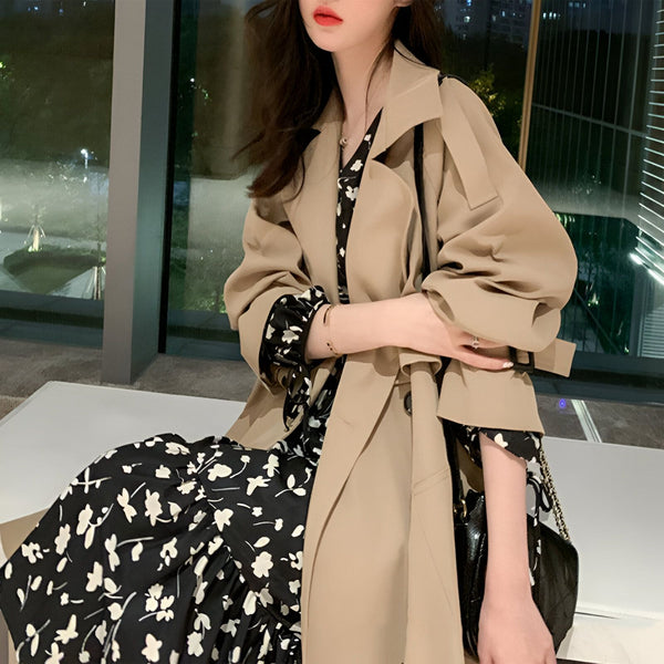 Femme portant un kimono long à fleurs noires et blanches sous un trench beige. Vêtements traditionnels japonais revisités. Boutique de kimonos en ligne.