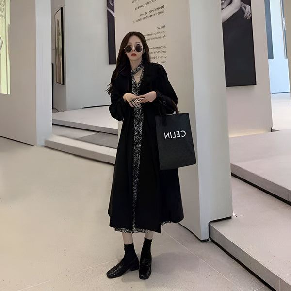 Femme portant un kimono long noir avec motifs floraux, lunettes de soleil, et un sac noir. Collection de kimonos élégants pour toutes les occasions.