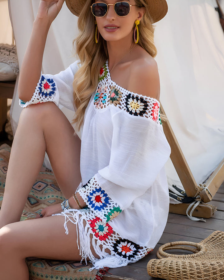 Femme portant un kimono blanc à épaules dénudées avec des motifs floraux colorés en crochet. Accessoires : lunettes de soleil, chapeau de paille et boucles d'oreilles. Vêtements de plage, style bohème.