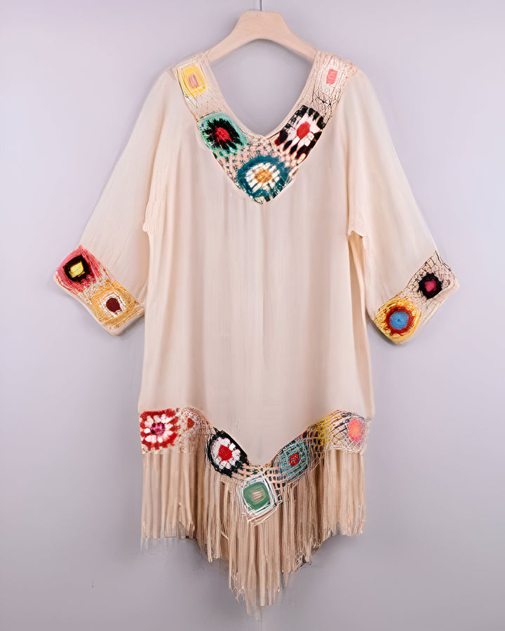 Kimono beige à motifs colorés et franges, style bohème. Vêtement ample sur cintre, idéal pour un look décontracté. Notre collection de kimonos uniques.