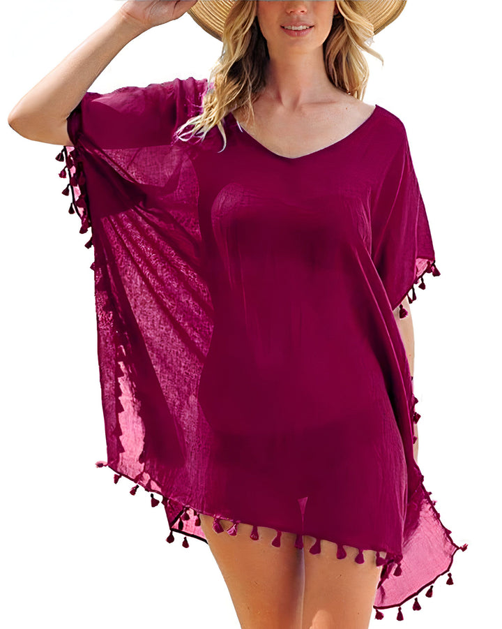Femme portant un kimono de plage violet avec des pompons. Kimono de plage léger, idéal pour l'été. Découvrez notre collection de kimonos pour femme.