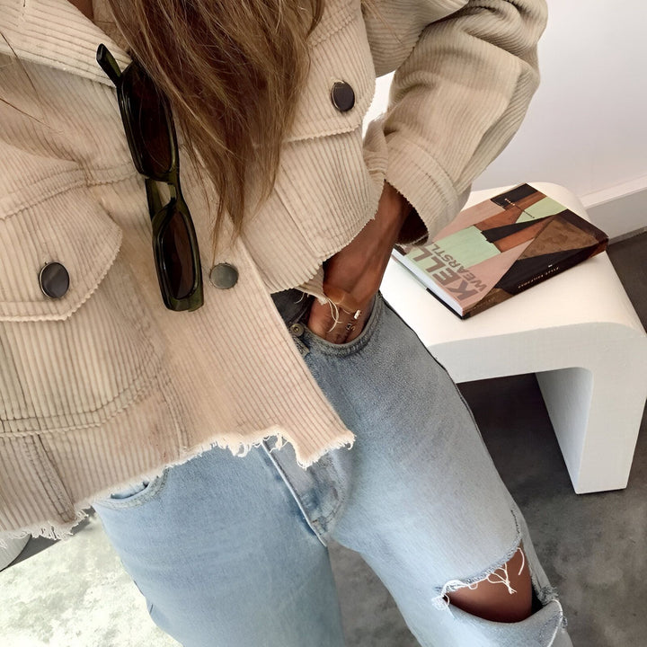 Veste beige en velours côtelé, portée avec un jean bleu clair et des lunettes de soleil accrochées. Style décontracté et tendance. Parfait pour compléter un kimono.