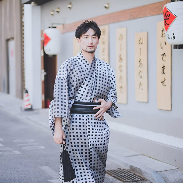 Homme portant un kimono traditionnel à motifs carreaux noirs et gris. Vente de kimonos et vêtements japonais pour hommes et femmes. Mode et élégance japonaise.