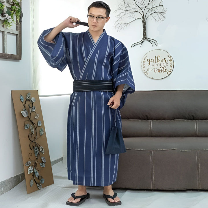 Homme portant un kimono japonais rayé bleu et blanc avec une ceinture noire et des sandales traditionnelles. Vêtements traditionnels japonais en vente.