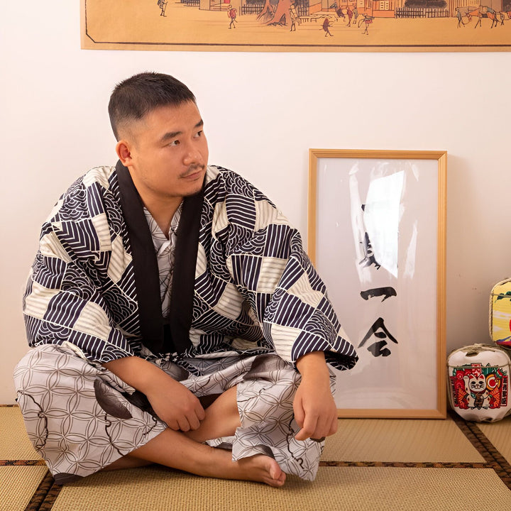 Homme portant un kimono traditionnel japonais à motifs, assis sur un tatami. Découvrez notre collection de kimonos authentiques.