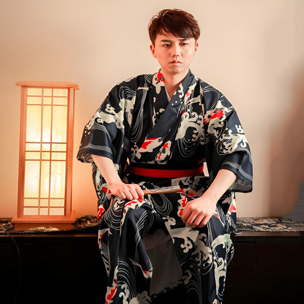 Homme portant un kimono japonais noir avec motifs de vagues et carpes koï rouges. Ceinture rouge. Vente de kimonos traditionnels et modernes en ligne.