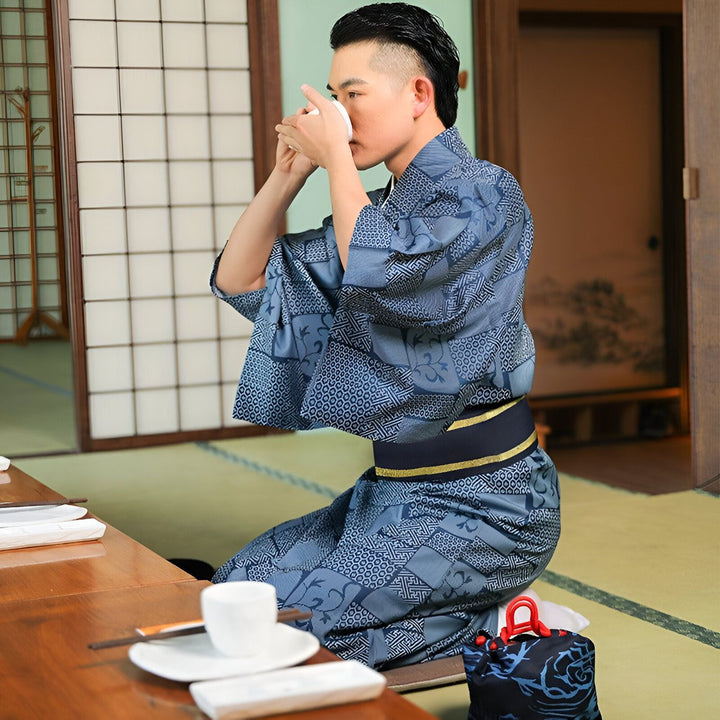 Homme en kimono bleu à motifs buvant du thé, assis sur un tatami. Vente de kimonos traditionnels japonais.