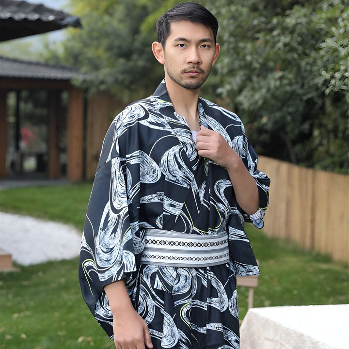 Homme portant un kimono japonais noir et blanc à motifs, ceinture obi blanche. Vêtements traditionnels, style asiatique.