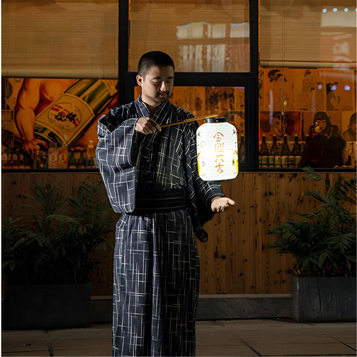 Homme en kimono traditionnel bleu et noir tenant une lanterne japonaise blanche. Vêtements japonais, yukata, style vestimentaire japonais.