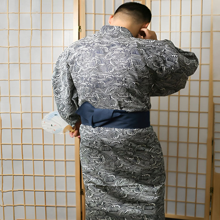Homme portant un kimono japonais avec motifs de vagues, ceinture obi bleue. Kimonos traditionnels et modernes disponibles à l'achat.