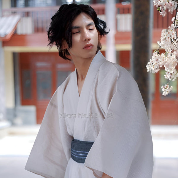 Homme portant un kimono japonais beige avec une ceinture obi grise, devant un décor traditionnel. Vente de kimonos authentiques pour hommes et femmes.