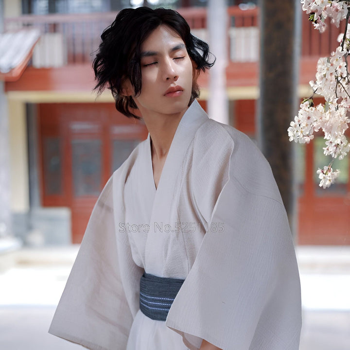 Homme portant un kimono japonais beige avec une ceinture obi grise, devant un décor traditionnel. Vente de kimonos authentiques pour hommes et femmes.