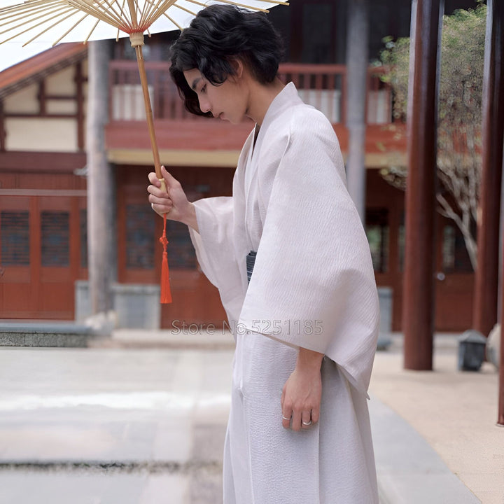 Homme portant un kimono japonais traditionnel blanc et tenant une ombrelle. Kimonos disponibles à l'achat.